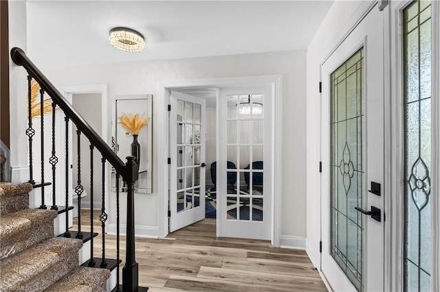 foyer entrance with french doors, baseboards, stairway, and light wood-type flooring