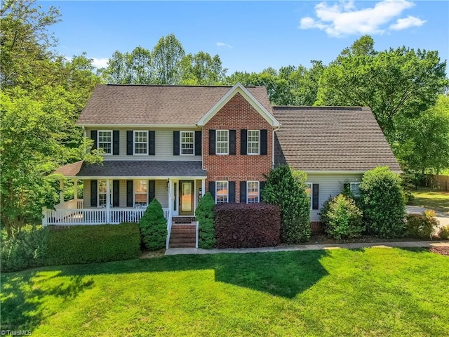 colonial inspired home featuring a porch and a front lawn