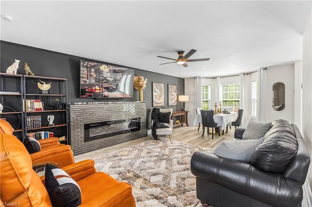 living room featuring a brick fireplace, ceiling fan, and wood finished floors