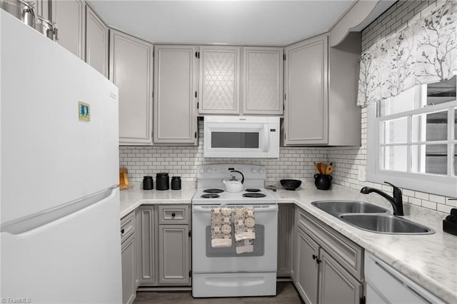 kitchen featuring sink, white appliances, gray cabinets, dark hardwood / wood-style flooring, and decorative backsplash