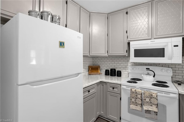 kitchen featuring tasteful backsplash, gray cabinets, and white appliances