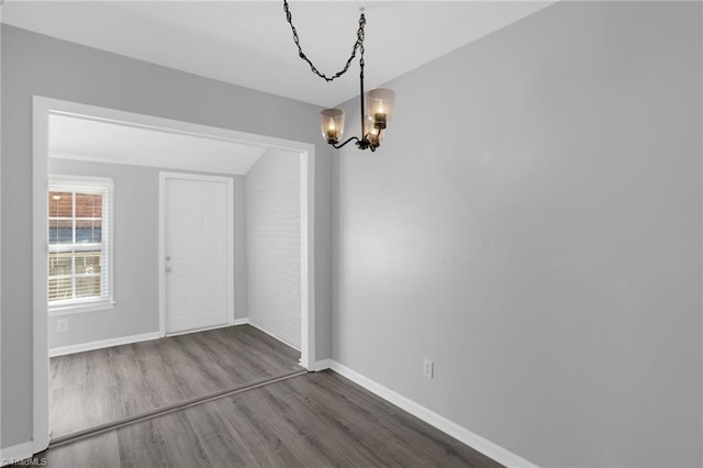 unfurnished dining area with vaulted ceiling, dark hardwood / wood-style floors, and a chandelier