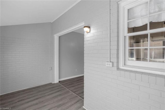 hall with dark hardwood / wood-style floors and brick wall