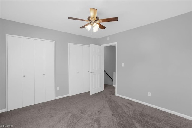 unfurnished bedroom featuring multiple closets, carpet flooring, and ceiling fan