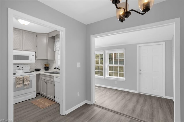 kitchen featuring gray cabinets, tasteful backsplash, sink, white appliances, and light hardwood / wood-style flooring