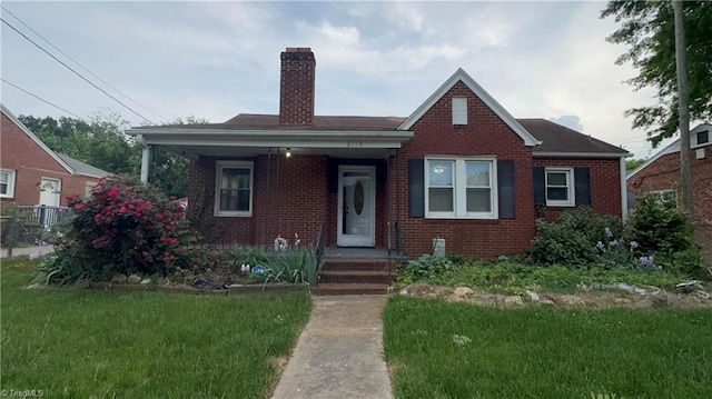 bungalow-style house with brick siding, fence, a chimney, and a front yard