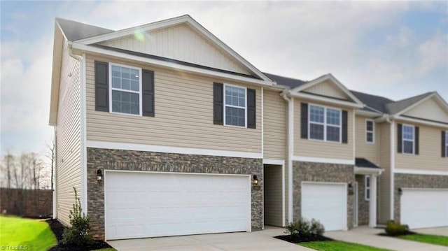 view of front of house with an attached garage, stone siding, and concrete driveway