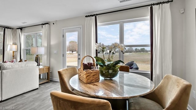 dining space with baseboards, visible vents, and light wood-style floors