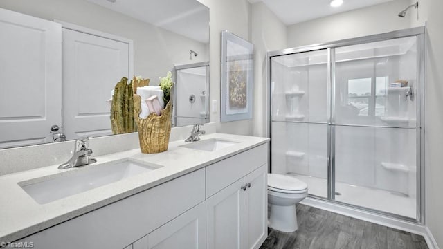 bathroom with a shower stall, wood finished floors, toilet, and a sink
