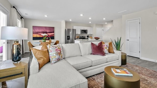 living area with baseboards, wood finished floors, and recessed lighting