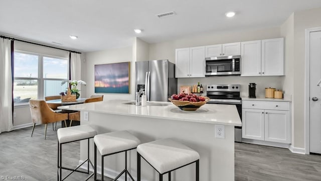 kitchen with visible vents, appliances with stainless steel finishes, white cabinetry, a sink, and a breakfast bar area
