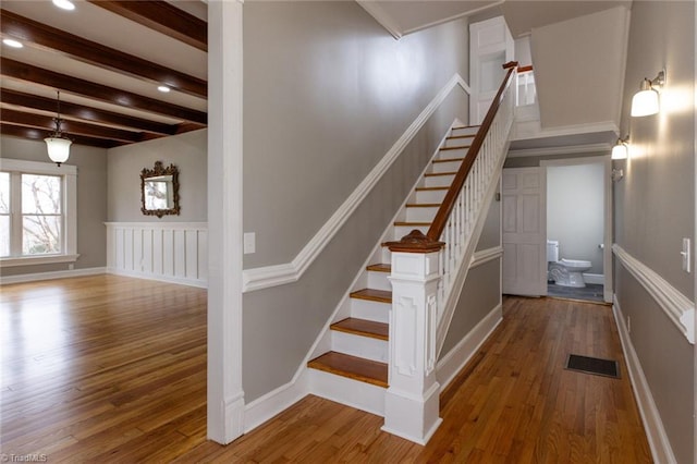 stairs featuring wood-type flooring and beam ceiling