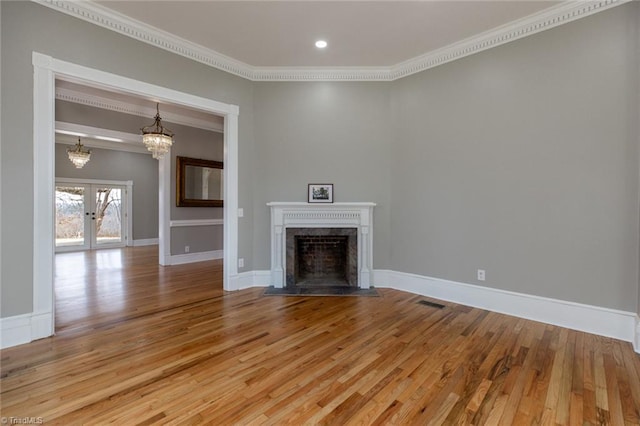 unfurnished living room with french doors, ornamental molding, a chandelier, and light hardwood / wood-style floors