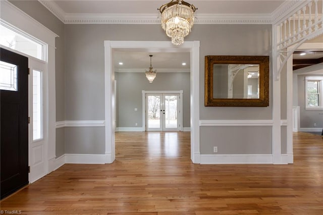 foyer with crown molding, hardwood / wood-style floors, a chandelier, and french doors