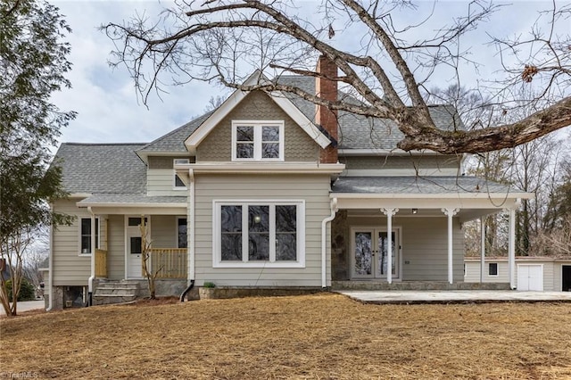 view of front of home featuring an outbuilding, covered porch, and a front yard