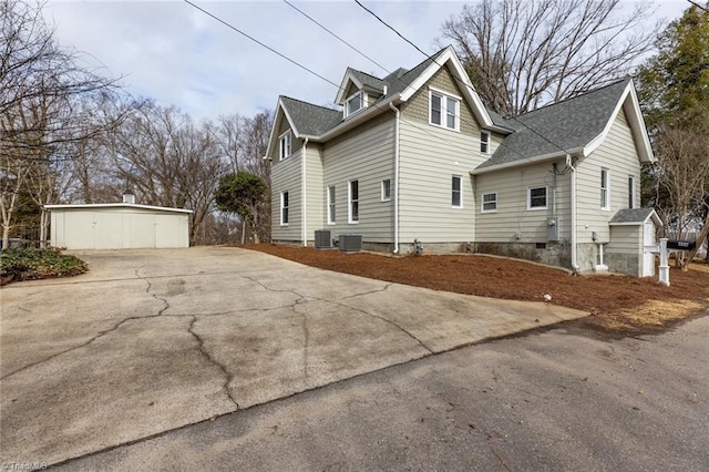 view of side of home featuring a garage, an outdoor structure, and central AC unit