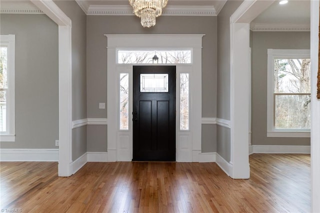 entryway featuring hardwood / wood-style floors, ornamental molding, and a chandelier