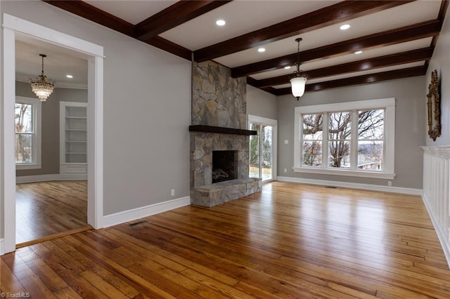 unfurnished living room with beam ceiling, a stone fireplace, and light wood-type flooring