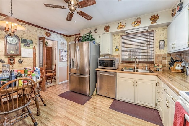 kitchen featuring white cabinets, sink, hanging light fixtures, light hardwood / wood-style floors, and stainless steel appliances