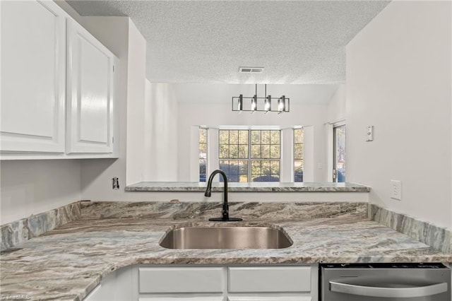 kitchen featuring white cabinets, light stone counters, a textured ceiling, stainless steel dishwasher, and sink