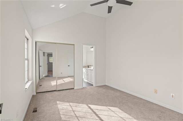 unfurnished bedroom featuring light carpet, high vaulted ceiling, a closet, and ceiling fan