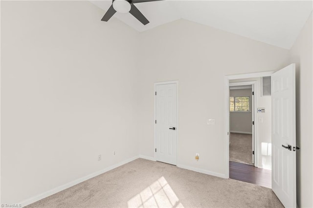 unfurnished bedroom with high vaulted ceiling, ceiling fan, and light colored carpet