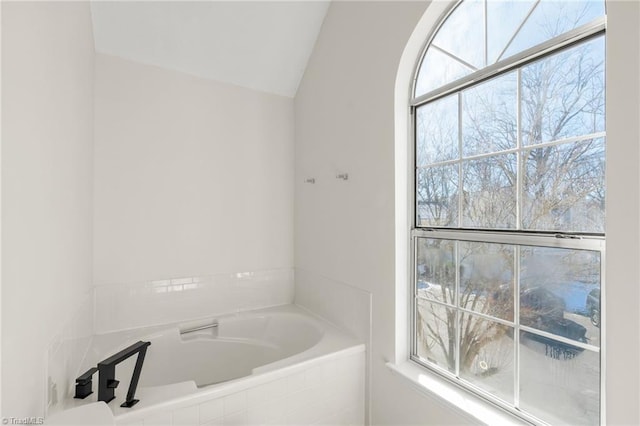 bathroom with vaulted ceiling and tiled tub