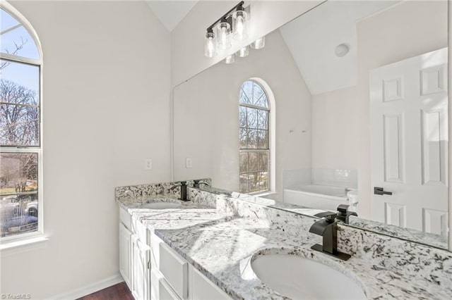 bathroom with lofted ceiling, vanity, and a tub