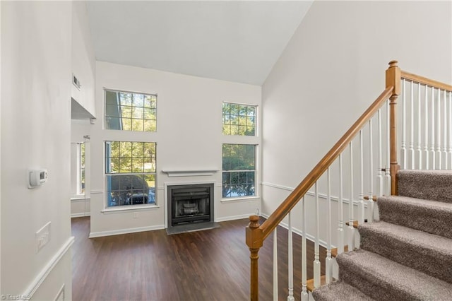 stairs with high vaulted ceiling and hardwood / wood-style floors