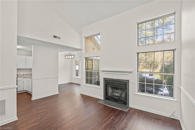 unfurnished living room with a towering ceiling and dark hardwood / wood-style floors