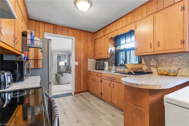 kitchen featuring light countertops, black electric range, tasteful backsplash, and light wood-style floors