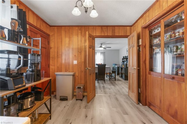 interior space with crown molding, wood walls, light wood finished floors, and an inviting chandelier