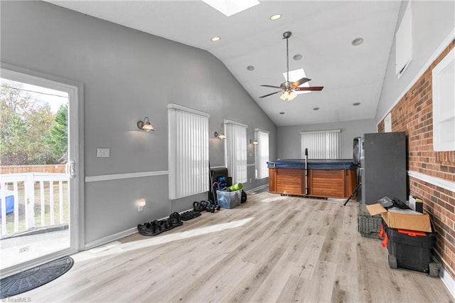 living area with baseboards, high vaulted ceiling, a ceiling fan, light wood-style flooring, and a skylight