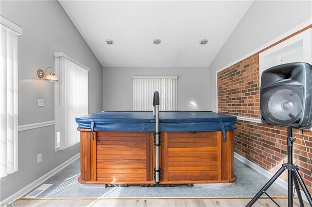 bar featuring visible vents, baseboards, brick wall, and vaulted ceiling