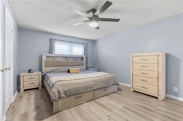 bedroom featuring ceiling fan, a textured ceiling, baseboards, and wood finished floors