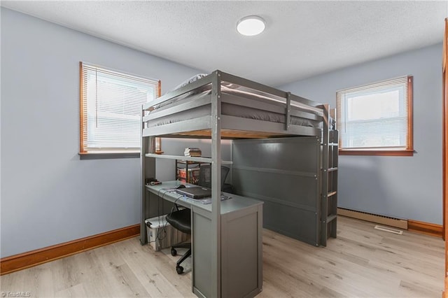 bedroom with light wood-type flooring, a baseboard radiator, baseboards, and a textured ceiling