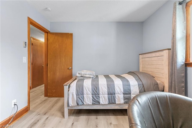 bedroom with baseboards, a textured ceiling, and wood finished floors