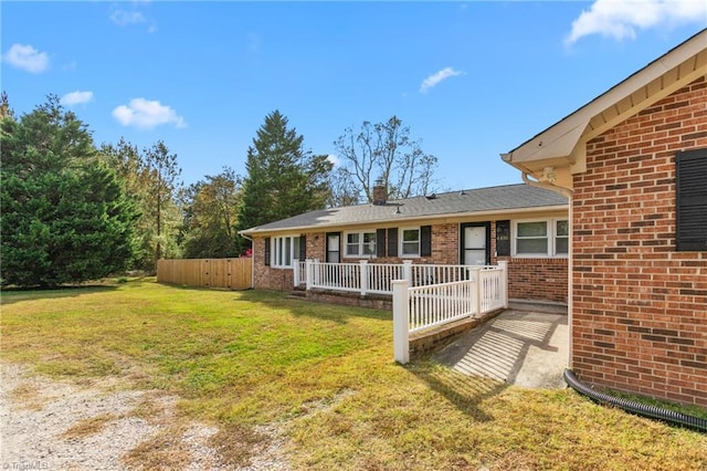 exterior space with a lawn, brick siding, fence, and a chimney