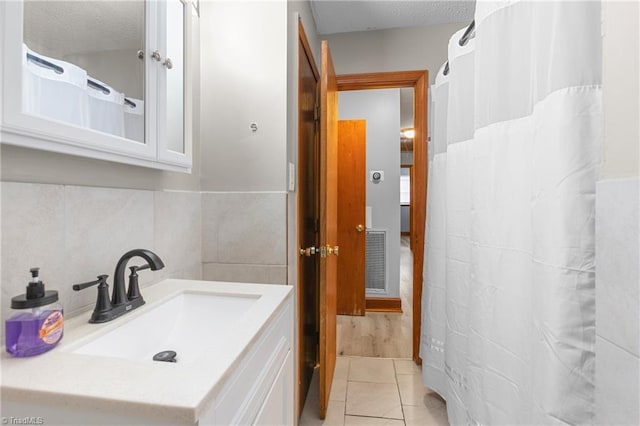 full bath with tile patterned floors, vanity, a textured ceiling, and visible vents