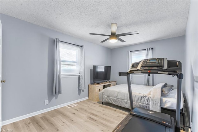bedroom with a textured ceiling, visible vents, multiple windows, and wood finished floors