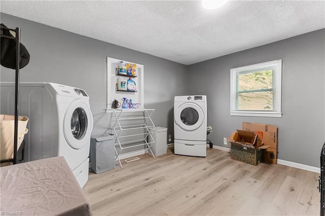 washroom with a textured ceiling, laundry area, washer / dryer, and light wood finished floors