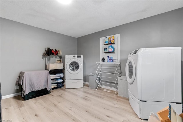 laundry area with a textured ceiling, laundry area, washer and clothes dryer, and light wood finished floors