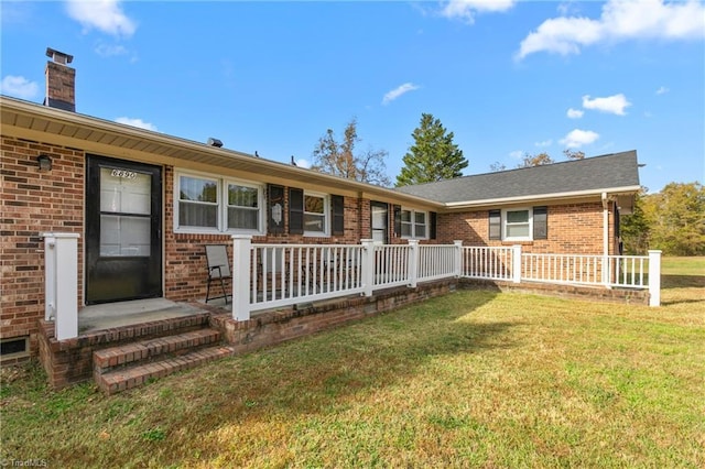 back of house featuring fence, a chimney, a yard, and brick siding