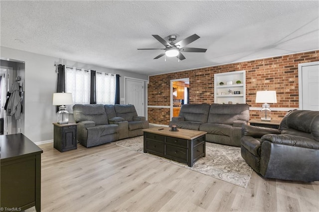 living room with brick wall, light wood finished floors, and a textured ceiling