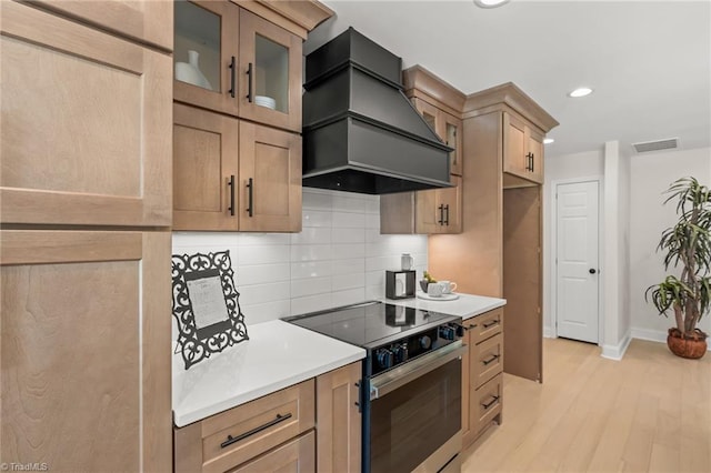 135 Boxwood Cir, Advance, NC 27006 - kitchen with stainless steel range with electric stovetop, custom range hood, tasteful backsplash, light countertops, and glass insert cabinets
