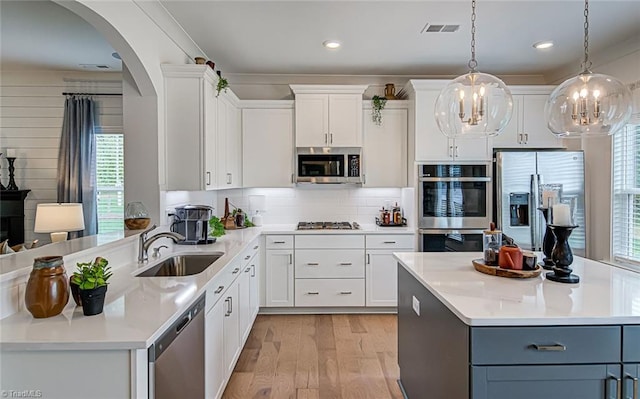 5927 Clouds Harbor Trl, Clemmons, NC 27012 - kitchen featuring appliances with stainless steel finishes, a sink, arched walkways, light wood-style flooring, and light countertops