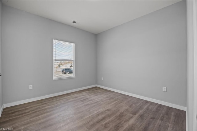 spare room with visible vents, baseboards, and wood finished floors