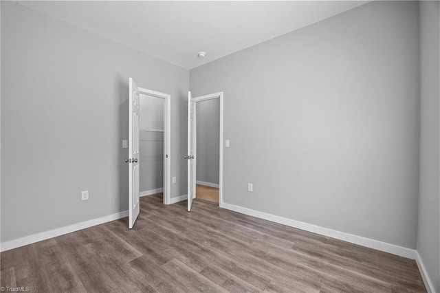 unfurnished bedroom with a closet, baseboards, and wood finished floors