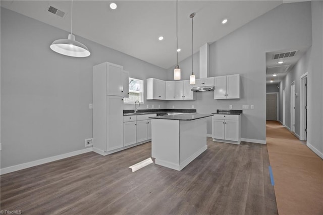 kitchen featuring under cabinet range hood, visible vents, white cabinets, and a sink