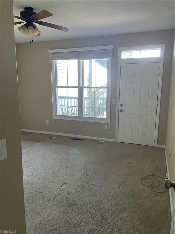 carpeted entryway featuring a textured ceiling and ceiling fan